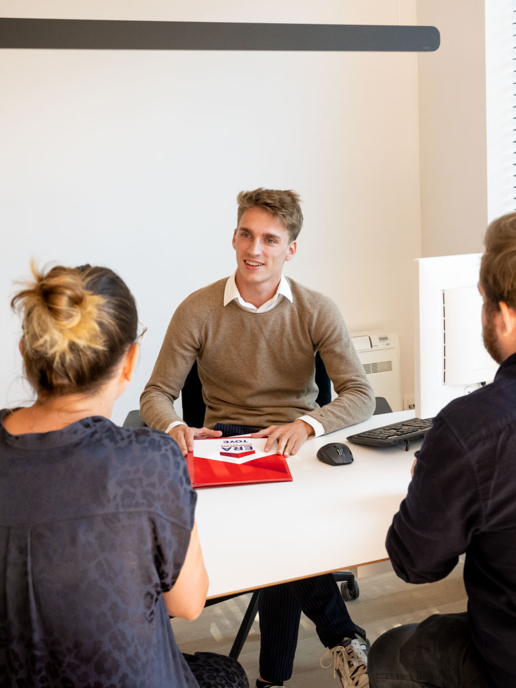 Een koppel zit aan tafel met een ERA makelaar om te onderhandelen over de verkoopprijs.