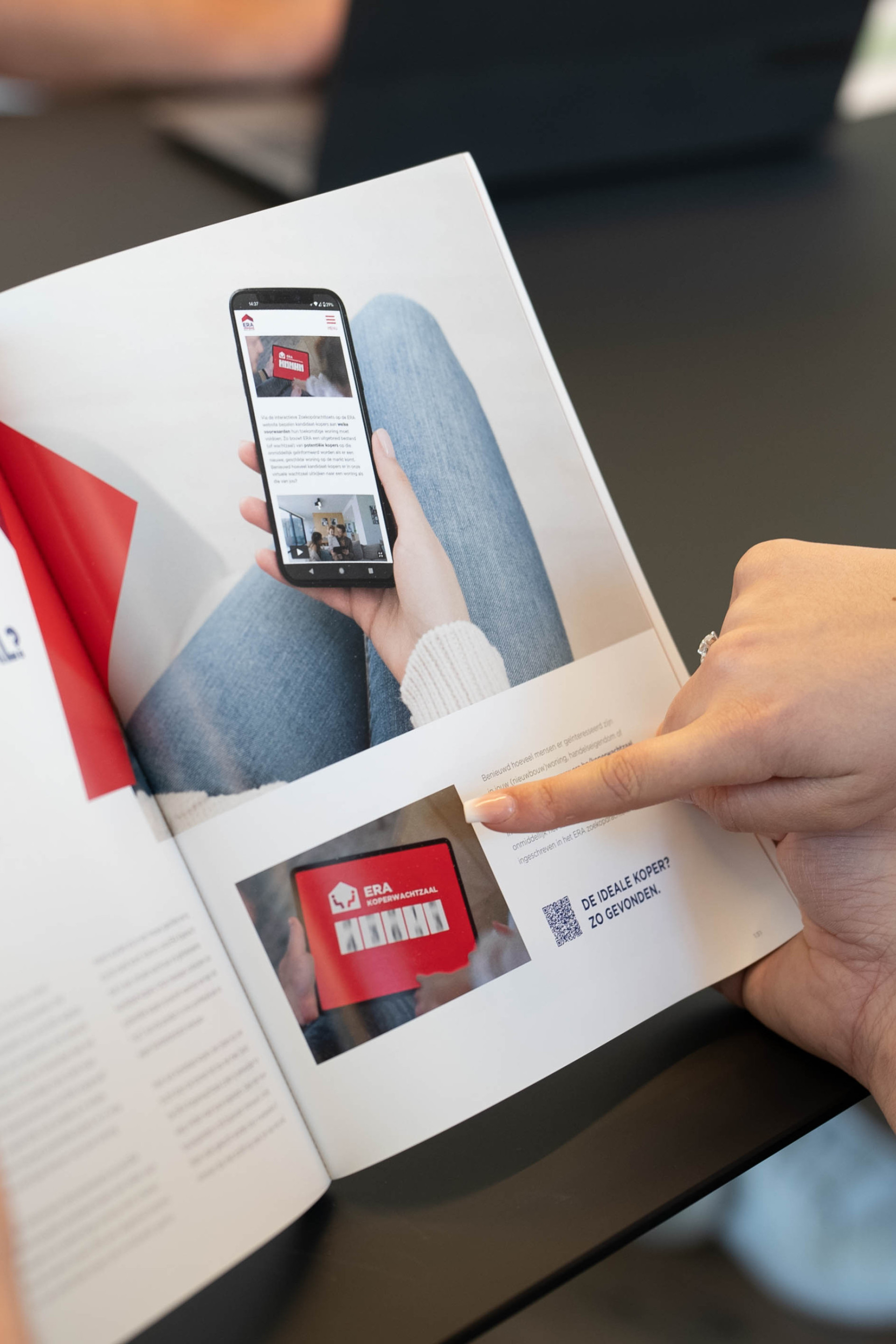 Een persoon wijst naar een pagina over de ERA Koperwachtzaal in een magazine.