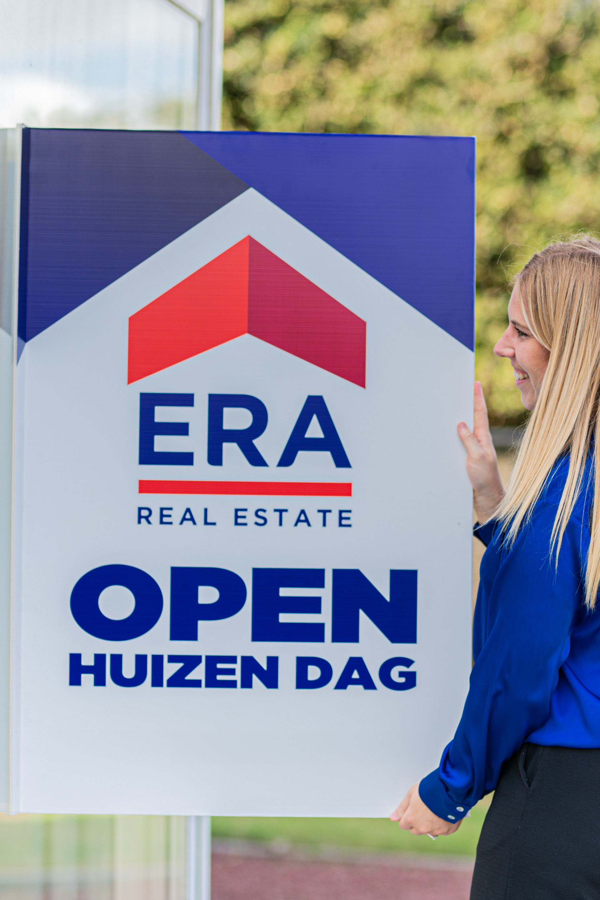 Een ERA makelaar hangt een ERA Open Huizen Dag V-Bord op.