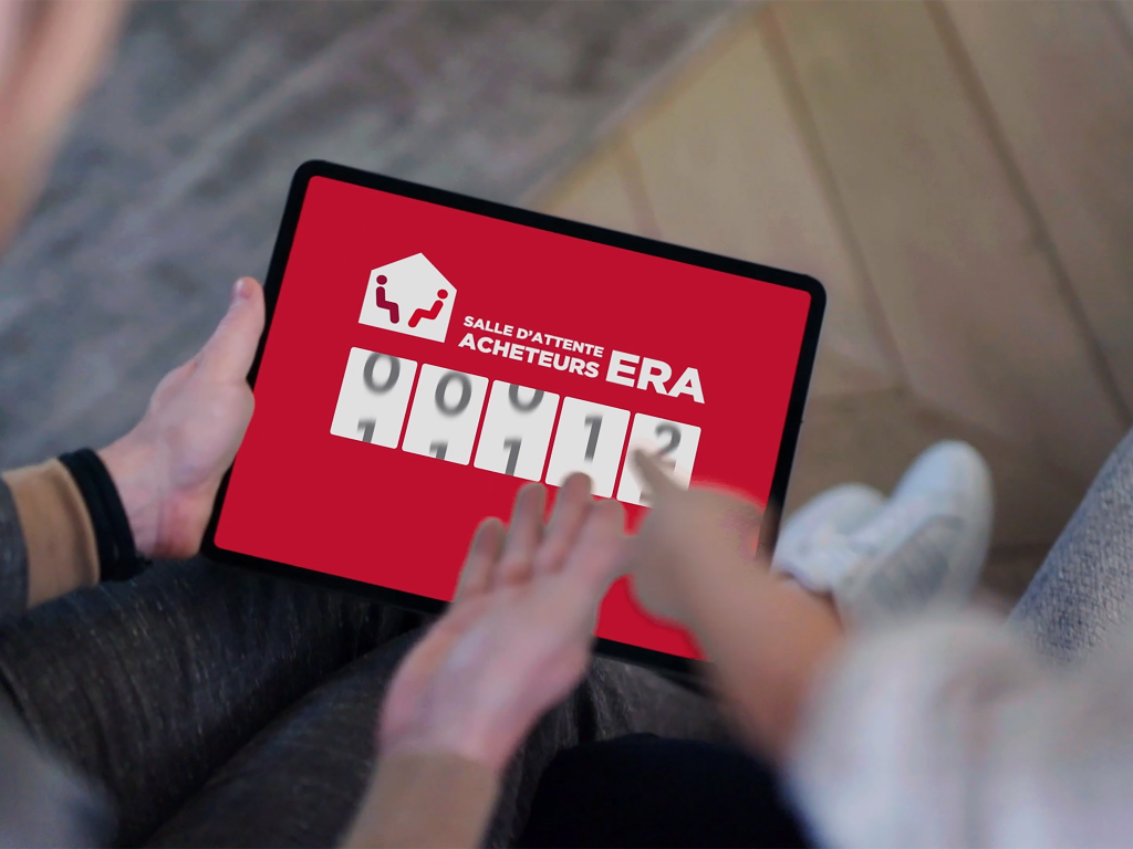 Deux personnes regardent la Salle d'Attente Acheteurs ERA sur une tablette.